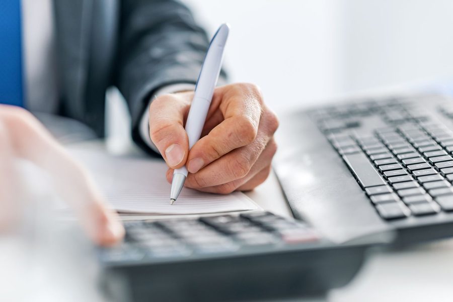 Tax advisor writing notes next to a calculator